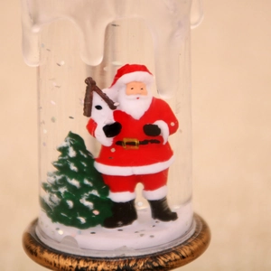 Close-up of a festive Christmas snow globe lamp featuring Santa Claus and a green tree