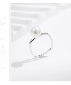 Macro detail of a minimalist S925 silver square ring set with a large white round pearl