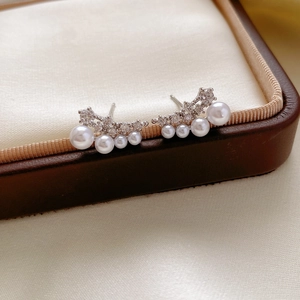 Detail of 18k gold-plated silver earrings with shimmering cubic zirconia and pearls