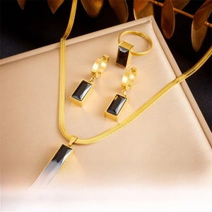Detail view of gold jewelry set featuring square black faceted stone pendant and ring