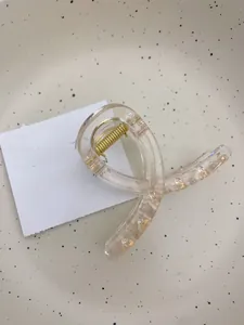 Gros plan d'une pince à cheveux minimaliste en acrylique avec ressort doré
