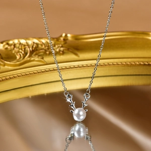 Macro view of elk antler pendant with white pearl on silver stainless steel chain
