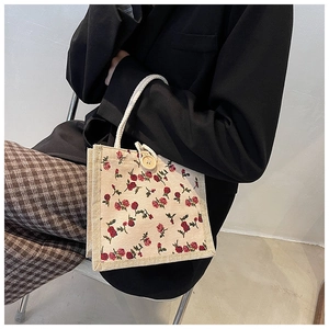 Detail of floral canvas handbag with woven rope handle and decorative wooden button closure