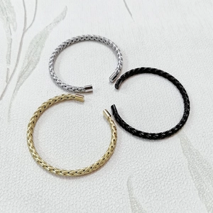Three textured braided stainless steel cuff bracelets in silver, gold and black