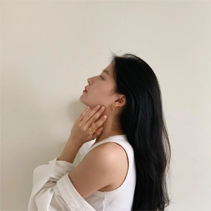 Close-up of minimalist gold jewelry set including twist hoop earrings and dainty ring