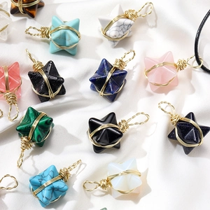 Natural crystal Merkaba star pendants with wire wrap detail on white fabric background