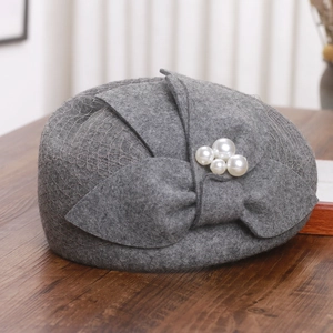 Detail of wool felt beret featuring bow decoration, white pearls, and delicate veil mesh