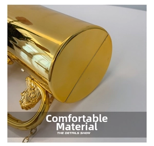 Detailed close-up of golden cylindrical evening bag with lion head relief and chain