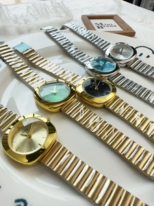 Detail of luxury square quartz watches in gold and silver steel bands on a white plate
