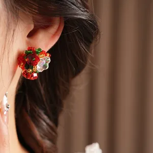 Vintage style floral cluster stud earrings with red and green beads worn by a model