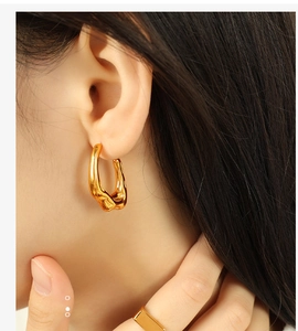 Close-up of irregular threaded gold earrings with a stylish streamlined metal texture