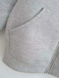 Close-up of heather grey knitted hoodie with metal zipper and reinforced pocket stitching