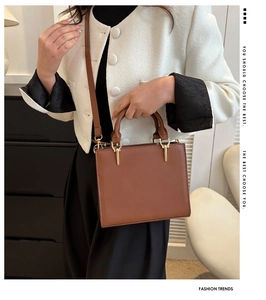 Detail of a brown structured handbag with stitching, gold hardware and slim shoulder strap