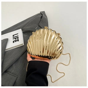 Handheld view of a luxury gold shell-shaped evening clutch bag with glossy metallic finish