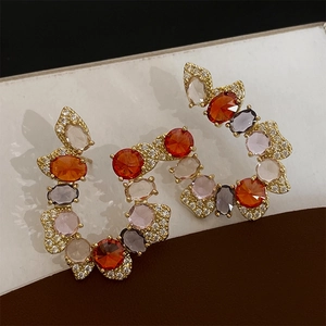 Detailed macro view of vintage C-shape gold earrings with colorful zircon and micro-pave crystals