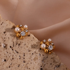 Macro view of gold cluster earrings with pearls and rhinestones on elegant silk and stone