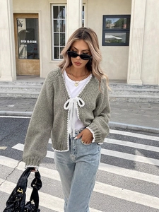 Chic grey knit cardigan with lace trim and white bow ties shown on a city street