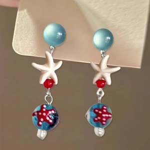 Macro shot of sea star earrings with blue beads and ocean-themed resin details