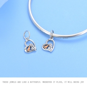 Detail view of heart charms with girl and cat motif, inlaid cubic zirconia on silver bracelet