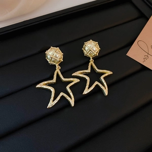 Detailed close-up of golden geometric star earrings with textured hammered finish