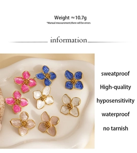 Détail de boucles d'oreilles fleurs en bleu, rose et blanc sur un plateau ondulé