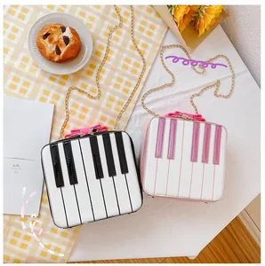 Detail of piano-shaped crossbody bag with keyboard design and pink bow accents