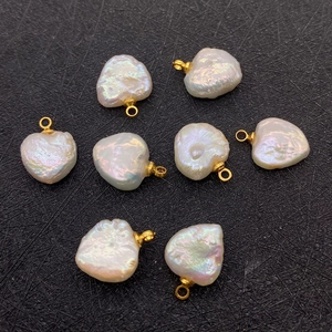 Macro detail of heart-shaped baroque freshwater pearl pendants with gold rings on black fabric
