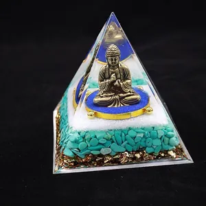 Macro view of crystal healing pyramid with bronze Buddha and layered crushed stones