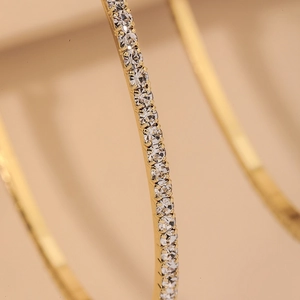 Detailed macro view of gold-plated hoop earrings featuring a row of sparkling crystals