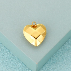 Faceted heart-shaped stainless steel gold pendant displayed on a textured box edge