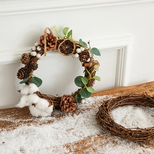 DIY Christmas wreath with pine cones and orange slices on a rustic snowy wooden surface
