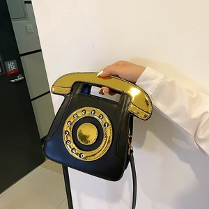 Detail of creative vintage telephone shaped handbag with black leather and gold dial