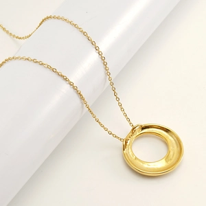 Détail d'un collier vintage en acier inoxydable plaqué or avec pendentif rond en zircon