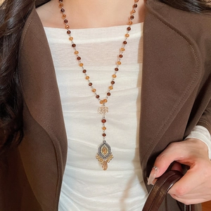 Close-up of vintage beaded long necklace with amber crystal teardrop pendant and metal filigree
