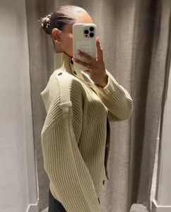 Detailed close-up of light beige ribbed knit cardigan featuring decorative button shoulder straps