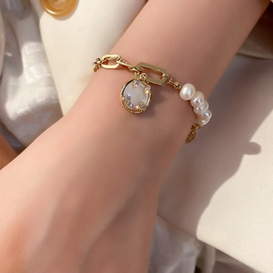 Detail of freshwater pearl and gold chain bracelet with a sparkling rhinestone smiley face