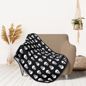Detail of soft flannel skull pattern blanket draped over a cozy armchair in a home setting