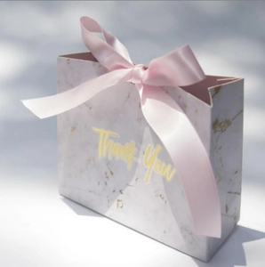 Detail of marble pattern wedding candy box featuring elegant pink ribbon and gold Thank You text