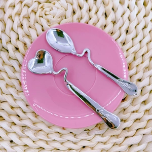 Close-up of two stainless steel hanging coffee spoons with heart and oval shapes
