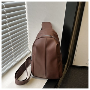 Detail of coffee brown crossbody bag with matte finish and stylish pleated texture