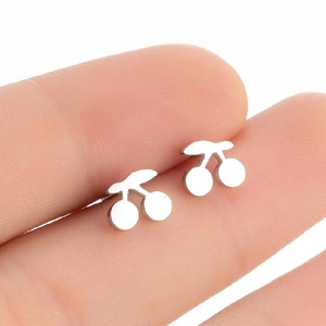 Minimalist silver cherry stud earrings shown on fingertip to display small size