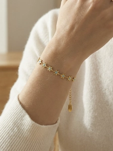 Close-up of gold daisy chain bracelet with blue enamel petals and K18 engraving