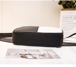 Detailed side and bottom view of black and white PU leather crossbody bag on desk