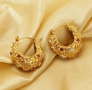 Detailed macro of vintage 18K gold hoop earrings with red gems on silk fabric