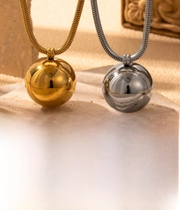Detail of titanium steel snake chain necklaces in gold and silver finish with ball pendant