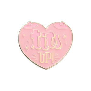 Pink heart enamel brooch with gold trim and Tits Up lettering on a white background