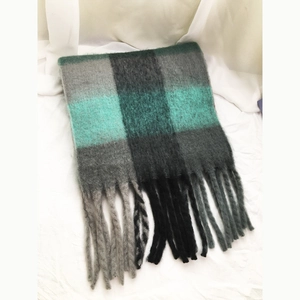Close-up of plaid scarf texture with grey, black and teal check pattern and fringe tassels