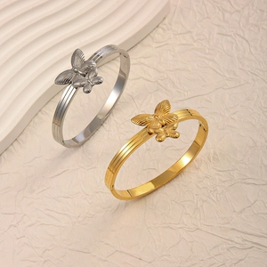 Double butterfly 18K gold and silver stainless steel bangles set on a textured background