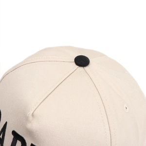 Detailed close-up of beige twill cotton baseball cap with black top button and embroidery