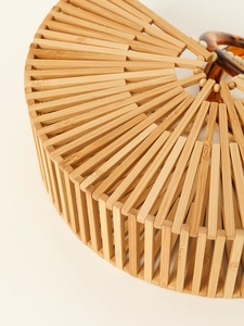 Detailed close-up of natural bamboo handbag showing radial slats and wooden bead texture